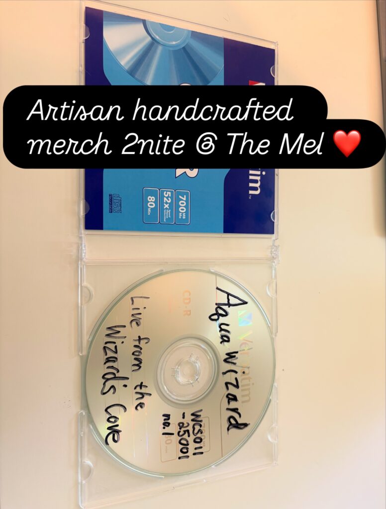 "Artisan handcrafted merch 2nite @ The Mel" text overlaid on a photo of the CD "Aquawizard, Live from the Wizard's Cove."